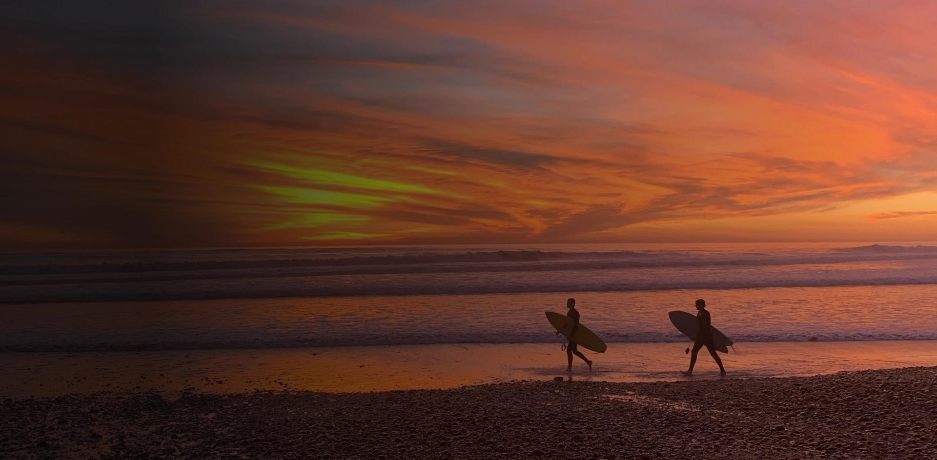 Silhouetted surfers walking at sunset on Huntington Beach — reflecting peace, renewal, and the journey toward recovery.