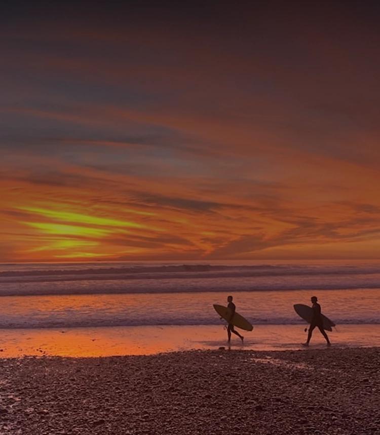 Silhouetted surfers walking at sunset on Huntington Beach — reflecting peace, renewal, and the journey toward recovery.