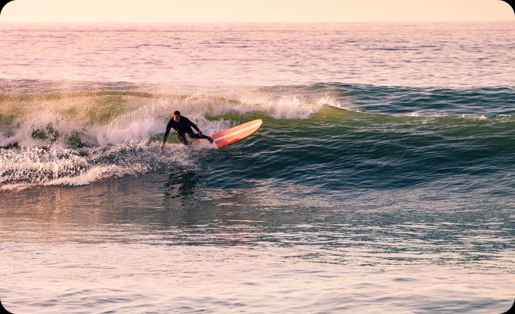 Man surfing at sunset in Newport Beach — reflecting the balance of recovery and lifestyle in local drug rehab programs.