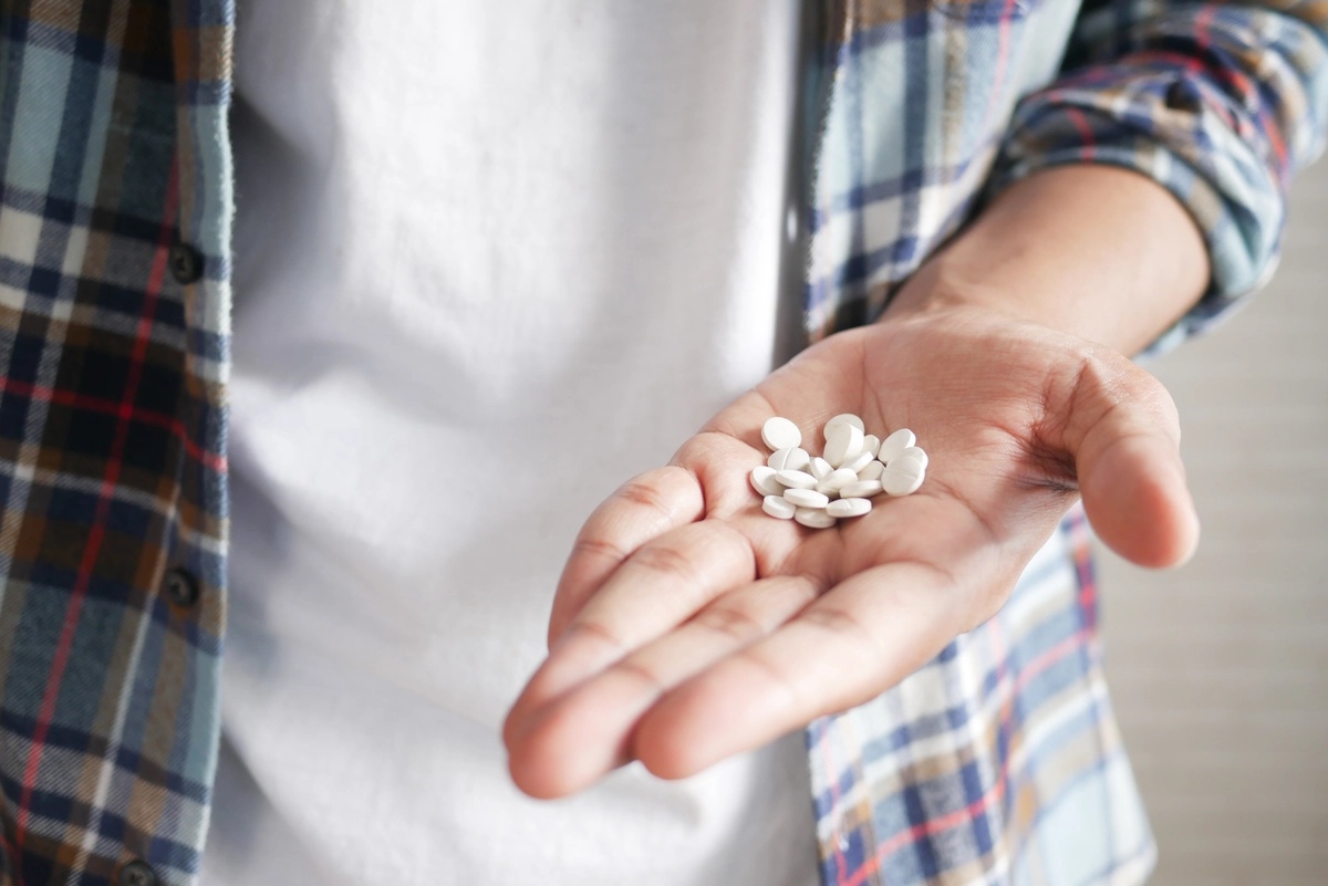 Stimulant Addiction: Man holding a handful of pills