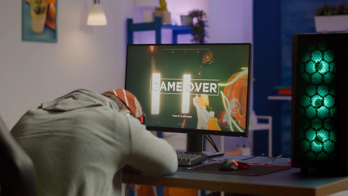 Video Game Addiction: Man sleeping in front of a monitor with a "game over" screen