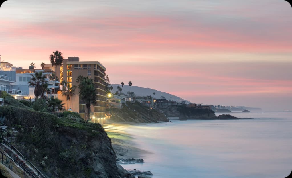 Sunset over Laguna Beach cliffs and oceanfront homes — peaceful environment supporting healing from drug and alcohol addiction.