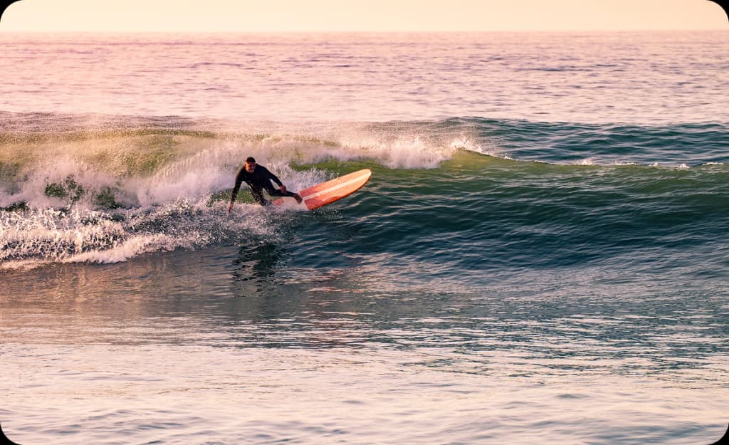 Man surfing at sunset in Newport Beach — reflecting the balance of recovery and lifestyle in local drug rehab programs.